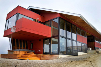 Inspiration för ett stort funkis rött hus, med två våningar, fiberplattor i betong och sadeltak