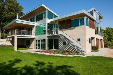 Modelo de fachada beige minimalista grande de dos plantas con revestimientos combinados y tejado plano