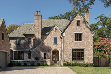 Large elegant red two-story brick house exterior photo in Other with a hip roof, a shingle roof and a brown roof