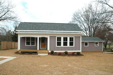 Immagine della facciata di una casa piccola country a un piano con rivestimento con lastre in cemento e tetto a capanna