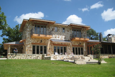 Modelo de fachada de casa beige actual grande de dos plantas con revestimiento de piedra