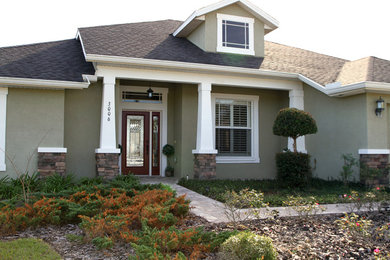 Example of a mid-sized arts and crafts green one-story stucco exterior home design in Tampa