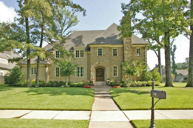 Large elegant beige two-story stone house exterior photo in Other with a hip roof and a shingle roof