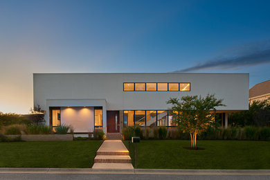 На фото: большой, двухэтажный, белый частный загородный дом в стиле модернизм с облицовкой из цементной штукатурки и плоской крышей