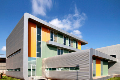 Ejemplo de fachada gris contemporánea extra grande de tres plantas con revestimiento de metal y tejado plano