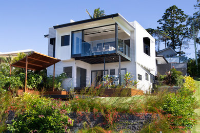This is an example of an expansive and white contemporary split-level detached house in Brisbane with a mixed material roof.