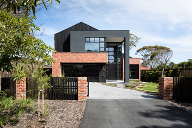 Diseño de fachada de casa negra urbana de dos plantas con revestimientos combinados y tejado a dos aguas