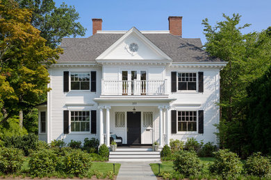 Elegant white two-story house exterior photo in Boston with a hip roof and a shingle roof