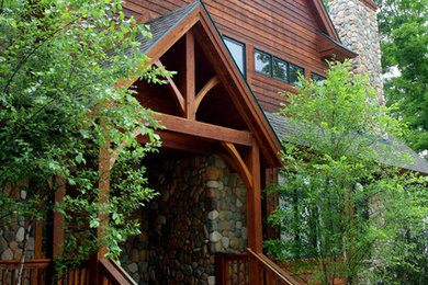 Ejemplo de fachada marrón rural grande de tres plantas con revestimiento de madera y tejado a dos aguas
