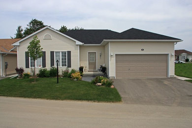 Small traditional beige one-story vinyl house exterior idea in Other with a hip roof and a shingle roof