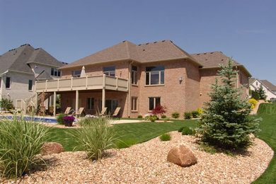 Imagen de fachada marrón de estilo americano grande de dos plantas con revestimiento de ladrillo y tejado a cuatro aguas