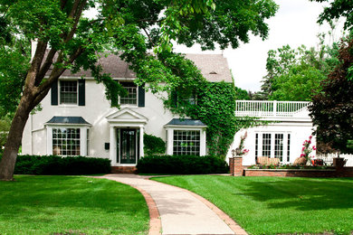Modelo de fachada de casa blanca clásica de tamaño medio de dos plantas con revestimiento de estuco, tejado a dos aguas y tejado de teja de madera