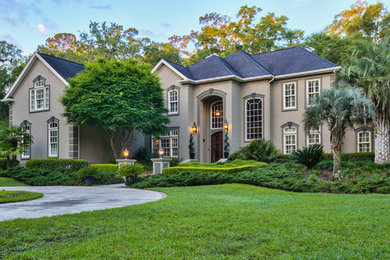Huge traditional beige two-story stucco exterior home idea in Jacksonville with a hip roof