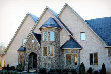 Example of a large classic beige two-story brick exterior home design in Other with a shingle roof