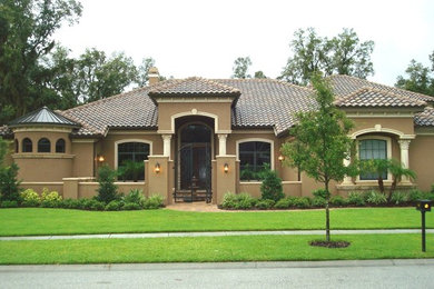 Inspiration for a large mediterranean brown one-story stucco house exterior remodel in Tampa with a hip roof and a tile roof