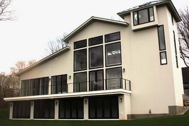 Diseño de fachada de casa beige actual de tamaño medio de dos plantas con revestimiento de madera y tejado a dos aguas