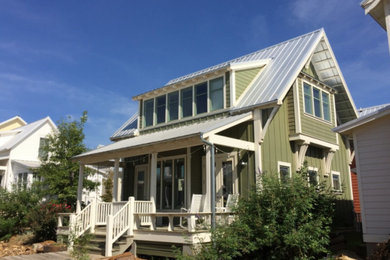 Example of a mid-sized arts and crafts green two-story wood exterior home design in Other with a metal roof