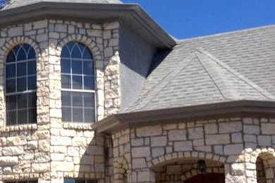 Diseño de fachada de casa beige de estilo americano de tamaño medio de dos plantas con revestimiento de piedra, tejado a cuatro aguas y tejado de teja de madera