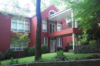 Ejemplo de fachada de casa roja clásica de tamaño medio de dos plantas con revestimiento de vinilo, tejado a dos aguas y tejado de metal