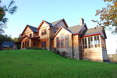 Esempio della facciata di una casa grande marrone classica a tre piani con rivestimento in legno