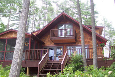 На фото: двухэтажный, деревянный, коричневый частный загородный дом среднего размера в стиле рустика с двускатной крышей