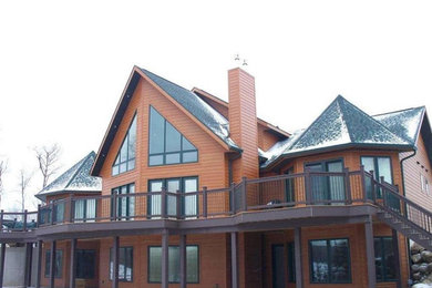 Imagen de fachada de casa marrón de estilo americano grande de dos plantas con revestimiento de madera, tejado a dos aguas y tejado de teja de madera