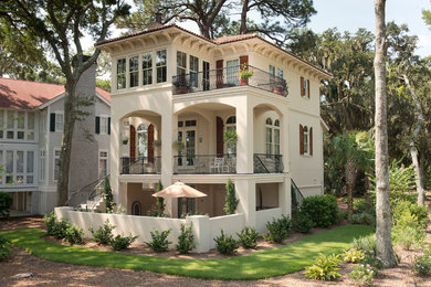 Diseño de fachada de casa beige tradicional grande de tres plantas con revestimiento de estuco, tejado plano y tejado de teja de barro