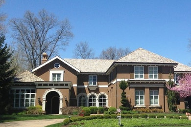 Пример оригинального дизайна: большой, двухэтажный, коричневый дом в классическом стиле с облицовкой из цементной штукатурки и двускатной крышей