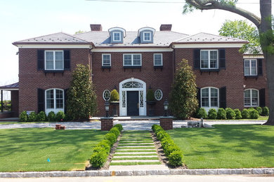 Mid-sized elegant red two-story brick house exterior photo in New York with a hip roof and a shingle roof