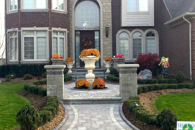 Mid-sized elegant red two-story brick house exterior photo in Detroit with a hip roof and a shingle roof