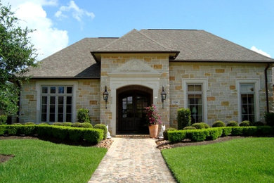 Example of a mid-sized classic beige one-story stone exterior home design in Austin with a hip roof