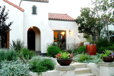 Imagen de fachada de casa blanca mediterránea de tamaño medio de dos plantas con revestimiento de estuco y tejado de teja de madera
