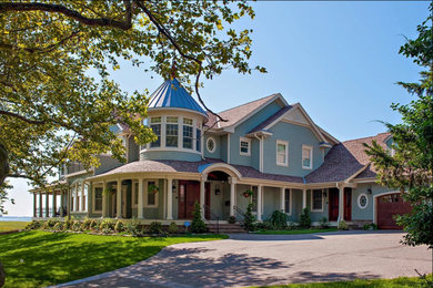 На фото: огромный, двухэтажный, деревянный, синий частный загородный дом в классическом стиле с двускатной крышей и крышей из гибкой черепицы