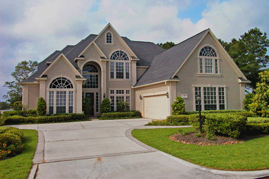 Example of a large classic beige two-story stucco exterior home design in Houston with a shingle roof