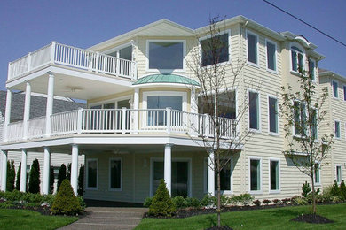 Foto de fachada de casa amarilla clásica grande de tres plantas con revestimiento de madera y tejado plano