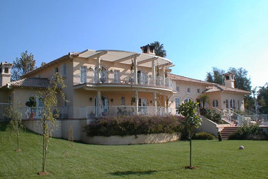 Стильный дизайн: большой, двухэтажный, бежевый частный загородный дом в средиземноморском стиле с облицовкой из камня, вальмовой крышей и черепичной крышей - последний тренд