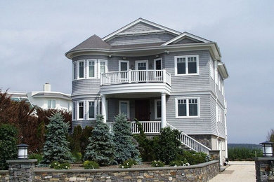 Immagine della facciata di una casa grande grigia stile marinaro a tre piani con rivestimento in legno e tetto a capanna