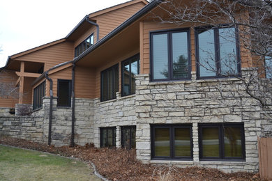 Imagen de fachada de casa marrón clásica renovada grande de tres plantas con revestimiento de aglomerado de cemento, tejado a cuatro aguas y tejado de teja de madera