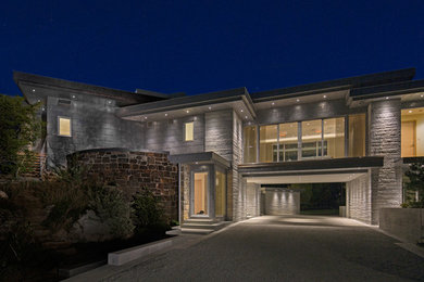 Réalisation d'une très grande façade de maison grise design en pierre à un étage avec un toit plat.
