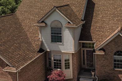This is an example of a large and brown traditional two floor detached house in Detroit with stone cladding, a pitched roof and a shingle roof.