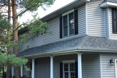 Imagen de fachada de casa gris tradicional de tamaño medio de dos plantas con revestimiento de vinilo, tejado a cuatro aguas y tejado de teja de madera