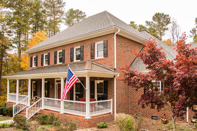 Large elegant red two-story brick exterior home photo in Raleigh