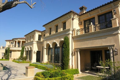 На фото: огромный, двухэтажный, коричневый дом в классическом стиле с облицовкой из цементной штукатурки и вальмовой крышей