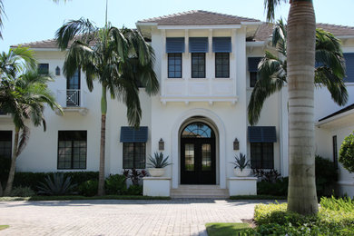 Example of a huge beach style white one-story stucco house exterior design in Miami with a hip roof and a shingle roof