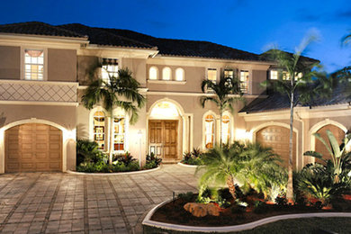 Large traditional beige two-story stucco exterior home idea in Miami