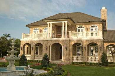 Inspiration for a large timeless brown two-story brick house exterior remodel in Tampa with a hip roof and a tile roof