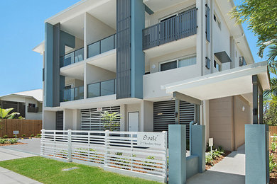 Modelo de fachada de piso beige contemporánea de tamaño medio de tres plantas con revestimiento de hormigón, tejado plano y tejado de metal