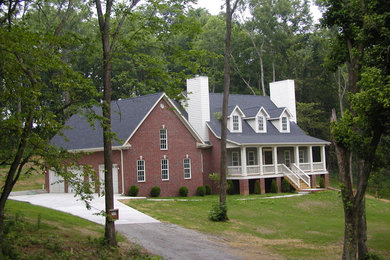 Immagine della facciata di una casa grande rossa classica a due piani con rivestimento in mattoni e tetto a capanna