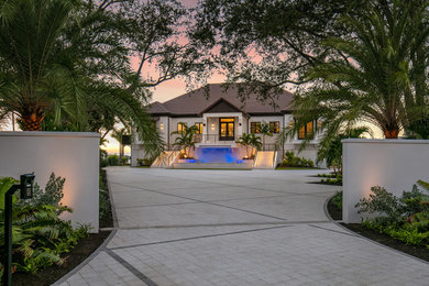 Example of a large trendy white two-story stucco house exterior design in Tampa with a hip roof and a tile roof