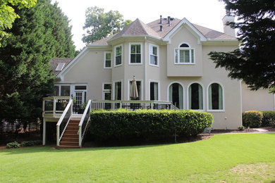 Ejemplo de fachada beige clásica grande de dos plantas con revestimiento de estuco y tejado a dos aguas
